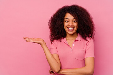 Young african american woman isolated on pink background showing a copy space on a palm and holding another hand on waist.