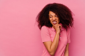 Young african american woman isolated on pink background touching back of head, thinking and making a choice.