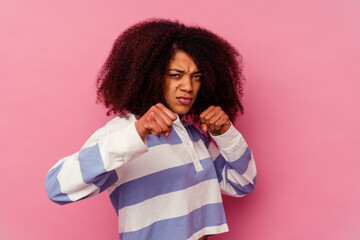 Young african american woman isolated on pink background throwing a punch, anger, fighting due to an argument, boxing.