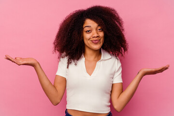Young african american woman isolated on pink background doubting and shrugging shoulders in...