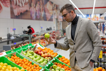 A man with face mask is buying fresh fruits in the supermarket.	