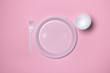 Plastic dishes on a pink background. Disposable tableware. Plastic products.