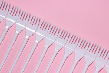 Plastic forks on a pink background. Disposable tableware. Plastic products.