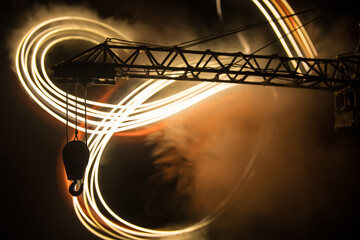 Abstract Industrial background with construction crane silhouette over amazing night sky with fog and backlight. Tower crane against the foggy sky at night.