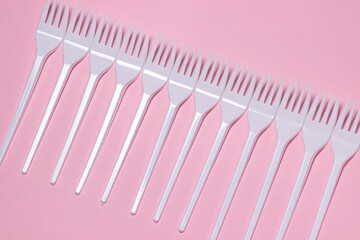 Plastic forks on a pink background. Disposable tableware. Plastic products.