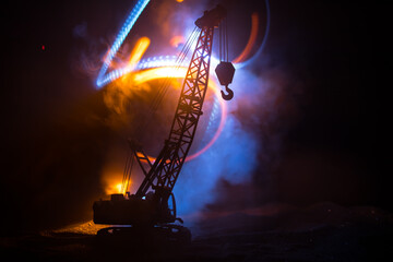 Abstract Industrial background with construction crane silhouette over amazing night sky with fog and backlight. Tower crane against the foggy sky at night.