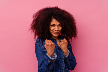 Young african american woman isolated on pink background throwing a punch, anger, fighting due to an argument, boxing.