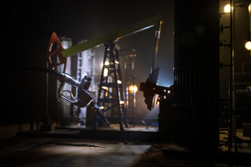 Creative concept. Silhouette of gasoline pistol miniature on dark toned foggy background. Close up. Industrial decorated elements on background.