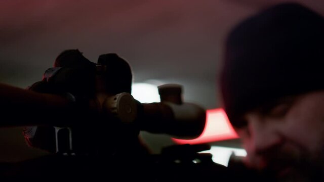 Killer holding sniper rifle. Serious gunman looking through scope of firearm