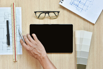 a top view of architect working desk with hand work on equipment for drawings pens sketched idea on wood table, the concept of modern technology for architectural working on wooden table