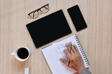 a top view of architect working desk with hand work on equipment for drawing pens sketched idea on wood table, the concept of modern technology for architectural working on wooden table