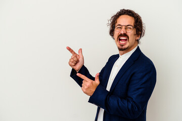 Young business man isolated on white background pointing with forefingers to a copy space, expressing excitement and desire.