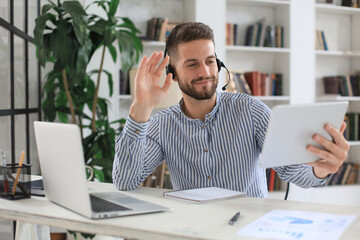 Confident man wearing headset speaking and watching business webinar training, listening to lecture.