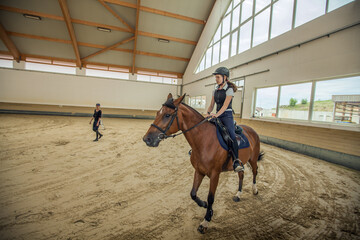 Closeup shot of a Slovenian girl riding a horse in an equestrian arena