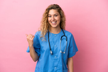 Young surgeon doctor woman isolated on pink background pointing to the side to present a product