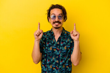 Young caucasian man wearing summer clothes isolated on yellow background indicates with both fore...