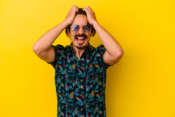 Young caucasian man wearing summer clothes isolated on yellow background laughs joyfully keeping hands on head. Happiness concept.