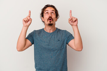 Young caucasian man isolated on white background pointing upside with opened mouth.