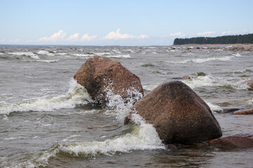 Waves crashing on rocks. Stones on a beach. Shore of Finnish Gulf. Windy weather over Baltic Sea shore. Stones facing sea waves. Waves crashing on water drops  