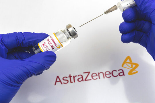Kharkov, Ukraine - April 18, 2021: Doctor in blue gloves holds Astrazeneca COVID-19 vaccine vial, injection byb using suringe close-up