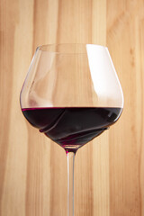 Elegant wineglass with red wine on bright vintage wooden background