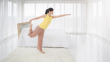 Fototapeta na wymiar Young beautiful Asian woman exercising in her bedroom in the morning 