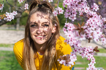 Obraz premium Portrait of young woman with shadows of almond blossoms in spring