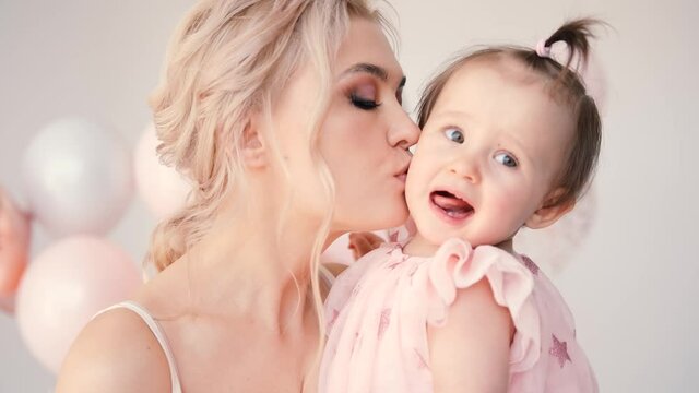 Little girl hugging with mom. A woman kisses her little daughter.