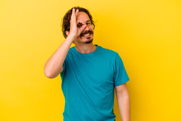 Young caucasian man isolated on yellow background excited keeping ok gesture on eye.