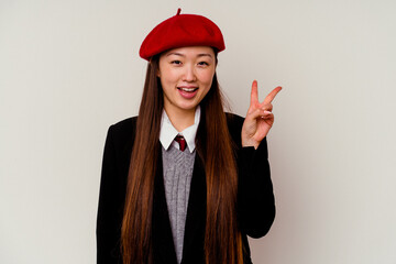 Young chinese woman wearing a school uniform isolated on white background joyful and carefree showing a peace symbol with fingers.