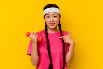 Young sport chinese woman isolated on yellow background person pointing by hand to a shirt copy space, proud and confident