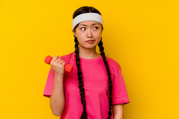 Young sport chinese woman isolated on yellow background confused, feels doubtful and unsure.