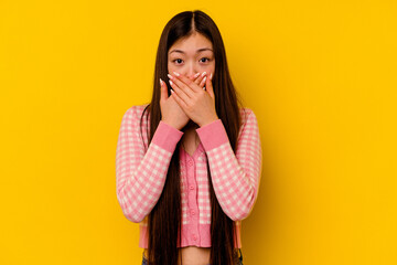 Young chinese woman isolated on yellow background shocked, covering mouth with hands, anxious to discover something new.