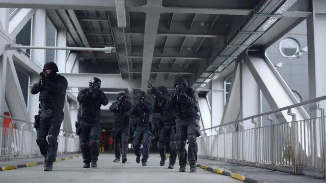 SWAT group with rifles moving on bridge. Police special forces looking around