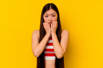 Young chinese woman isolated on yellow background biting fingernails, nervous and very anxious.