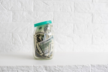 One hundred dollar bills in a glass jar