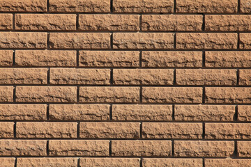 Decorative wall texture, background. Cream-colored grungy brick wall in stone style. The fragment of a new decorative bricklaying. The design of stylish exterior