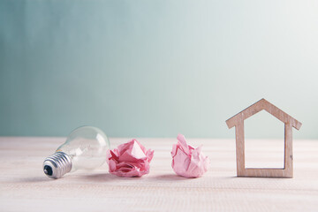Wood house with Light bulb on the table, a symbol for construction, Creative light bulb idea