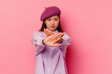 Young chinese woman isolated on pink background standing with outstretched hand showing stop sign,...