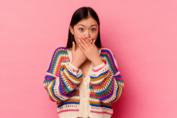 Young chinese woman isolated on pink background shocked covering mouth with hands.