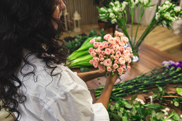 Attractive young woman florist is working in a flower shop.