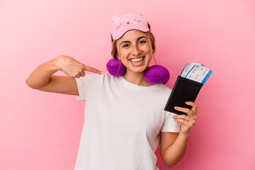 Young caucasian blonde woman holding a passport and tickets to travel isolated on pink background person pointing by hand to a shirt copy space, proud and confident