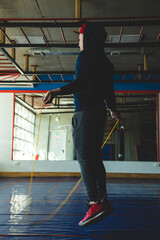 Young athlete man jumping rope in the training room