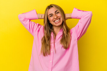 Young blonde caucasian woman isolated on yellow background feeling confident, with hands behind the head.