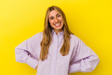 Fototapeta premium Young blonde caucasian woman isolated on yellow background confident keeping hands on hips.