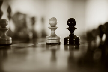 Two pawns - black and white. Wooden chess pieces on the chessboard.