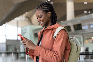 Happy black woman check message on smartphone after arrival of first flight after covid end in...