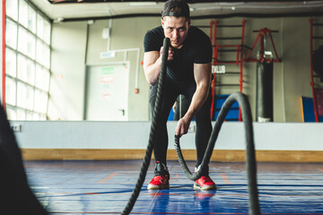Crossfit in the gym with ropes. The athlete is training.