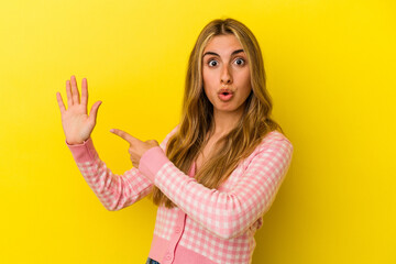 Young blonde caucasian woman isolated on yellow background smiling cheerful showing number five with fingers.