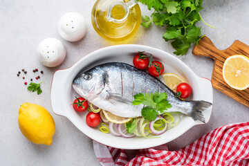 Dorado with vegetables ready for baking in ceramic dish. Top view. Cooking healthy dinner meal